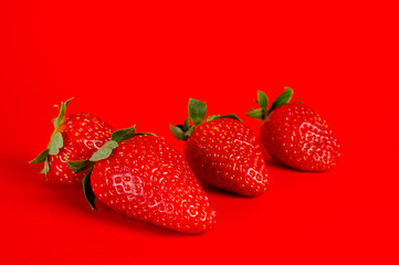 Strawberry ripe and juicy, very tasty and healthy, shot large on a bright red background.