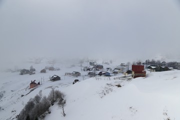 mountain landscape slopes covered with snow can be seen a tree fence and a house.savsat/artvin