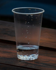 Vaso plástico sobre mesa de madera con fondo azul