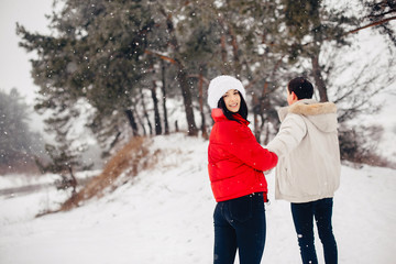 Fototapeta na wymiar Young couple in a winter park. Man with a red sharf. Lady in a red jacket