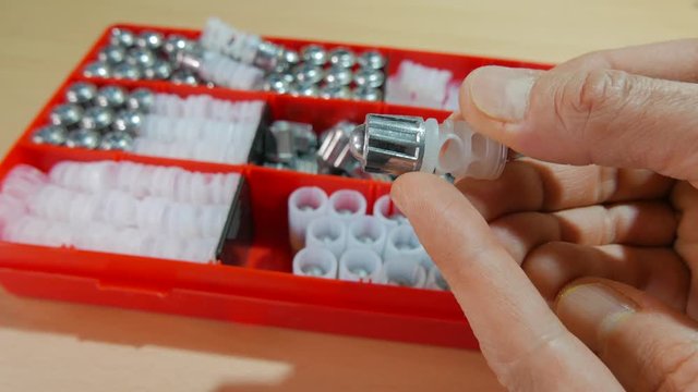 A box with components of hunting cartridges is on the table. A man chooses a 20-caliber bullet to equip a cartridge.