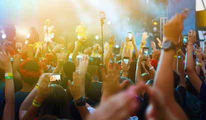 Hand with a phone records live music festival. People taking photographs with smart phone during a...