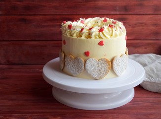  White cake with cookies and red hearts on a wooden background