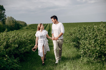 Fototapeta na wymiar Couple in a field. Blonde in a white dress. Man in a white shirt