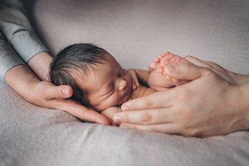 Fototapeta na wymiar newborn baby lying on the hands of parents. Imitation of a baby in the womb. beautiful little girl sleeping lying on her back. manifestation of love. Health care concept, parenthood, children's Day, m