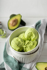 Balls of ice cream from avocado in a white porcelain bowl on a light background. Vertical image and close-up