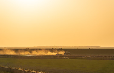 A tractor cultivating farmland in the last sunlight. Groningen, Holland.