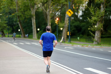 Middle age man jogging in Central Park of New York in summer evening.