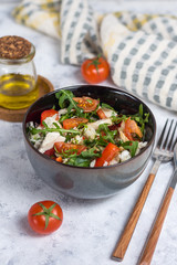 Salad with chicken, tomatoes and spinach with Peking cabbage in a dark bowl with a napkin and butter on a light background