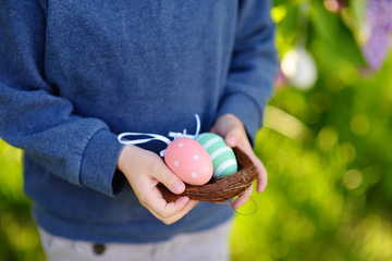 Pretty little boy wearing bunny ears hunting for easter eggs in spring park on Easter day.