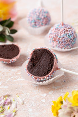  Sectional view Round chocolate cake pops with pink and yellow spring flowers on a marble background. Image with a vertical orientation.
