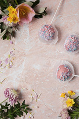 Background menu good. Round pop cake with pink and yellow spring flowers on a marble background. Image with  copy space.
