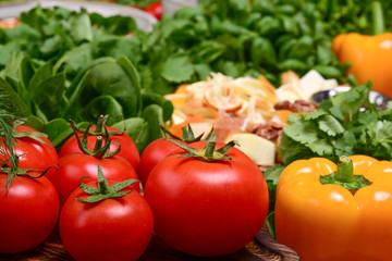 Large homegrown tomatoes surrounded by green tomatoes and spinach on a dark wooden table. Traditional georgian cuisine