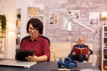Old lady in her 60s using modern technolgy in cozy living space