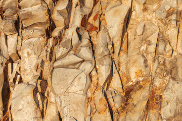 Closeup natural stone texture. Abstract nature rock background. Yellow-orange sharp stone plates.