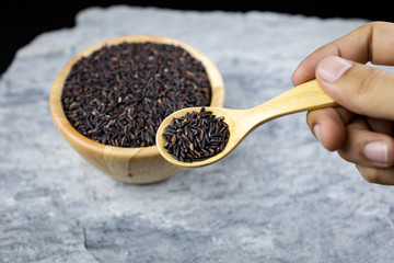 Hand hold a wooden spoon, riceberry on wooden spoon.