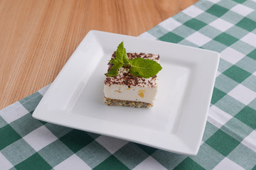 Traditional Italian dessert tiramisu served on a white plate with a mint leaf in a restaurant. Italian cuisine, dessert.
