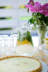 Peony flower vase and glass jug with lemonade on a wooden picnic table in summer. Family holiday.