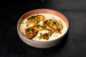 Serving Chkmeruli in a light plate on a black background
