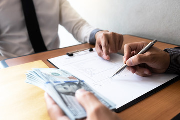 The businessman signed a contract agreement documents and receive a bribe from another businessman sitting in front at the office.