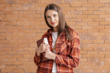 Beautiful young woman with book on brick background