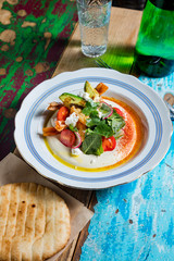 A bowl of creamy hummus with olive oil and pita chips.