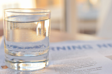 Glass of clean water and newspaper on table