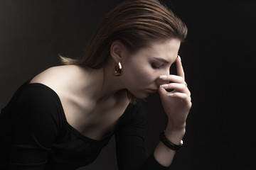 Portrait in the photo Studio of a brown-haired girl, on a black background in black clothes with open shoulders. Short hair.