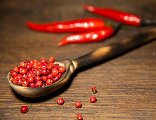 Red pepper seeds and chilli peppers on a wooden surface.