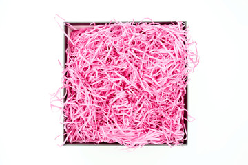 Shredded pink paper packing material in a square box. Pink spaghetti shredded packing paper used to...