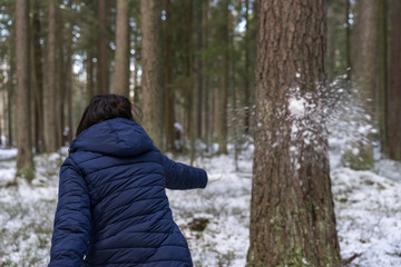 Fototapeta na wymiar woman throws a snowball at a tree. the snowball is breaking on a tree. winter fun