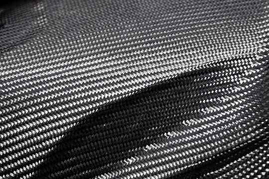 A close-up on a carbon fiber background of interwoven black and gray color from heavy-duty yarns for the production of light and durable elements in industry.