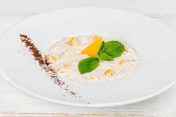 Boiled oatmeal with mango decorated with mint leaves