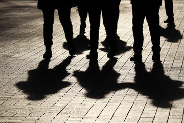 Silhouettes and shadows of people on the street. Crowd walking down on sidewalk, concept of...