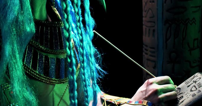 Close up of Thoth writing on a stone, looking at a big column with hieroglyphs