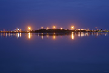 Night skyline, blue lake and sky divided by line of city lights reflecting in water