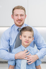Smiling father helps his son to put his tie
