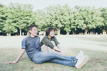 芝生に座る若いカップル（リラックス・公園）