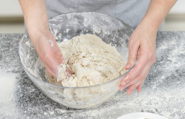 Female hands making dough in the kitchen at home. Top view