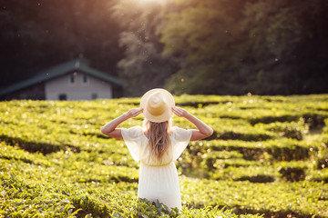 Rear view of a young girl In a bright peasant dress and hat enjoying green bushes and nature and clean forest air while walking in the countryside on a sunny summer day. Ecological travel concept