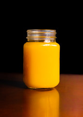 Jugo de naranja en un jar con fondo negro y madera 