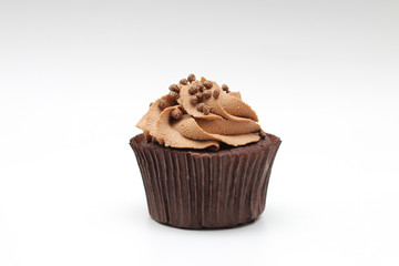 Isolated chocolate cupcake with cream top and crispy topping on a white background