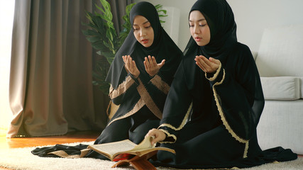 Portrait of an Asian Muslim man woman reciting Surah Al-Fatiha passage of the Qur'an in a single...