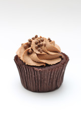 Isolated chocolate cupcake with cream top and crispy topping on a white background