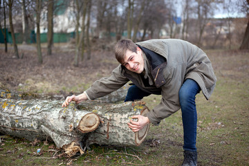 forest cleaning volunteers taking care of nature. A guy is trying drag to move a fallen tree.