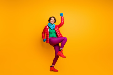 Fototapeta na wymiar Full length photo of funky excited lady raise hands leg ecstatic mood wear casual red overcoat blue scarf gloves green turtleneck trousers footwear isolated yellow color background