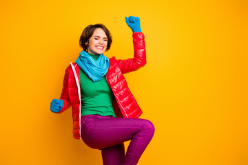 Photo of pretty funny lady ecstatic mood rejoicing celebrating success wear casual red overcoat blue scarf gloves green turtleneck pants isolated yellow color background