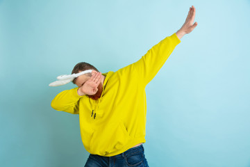 Making dab. Caucasian man as an Easter bunny with bright casual clothes on blue studio background....