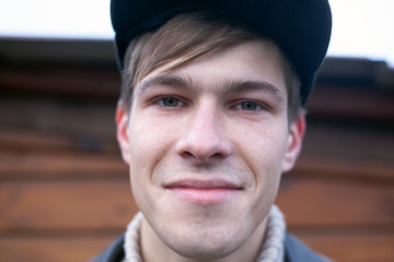 a guy in a cap 21-23 years old model looks smiling at the camera, portrait closeup