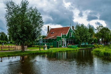 Fototapeta na wymiar Zaanse Schans, Holland, August 2019. North-east of Amsterdam is a small community located on the quay of the Zaan river. View of the charming village of wooden houses. Cloudy day.